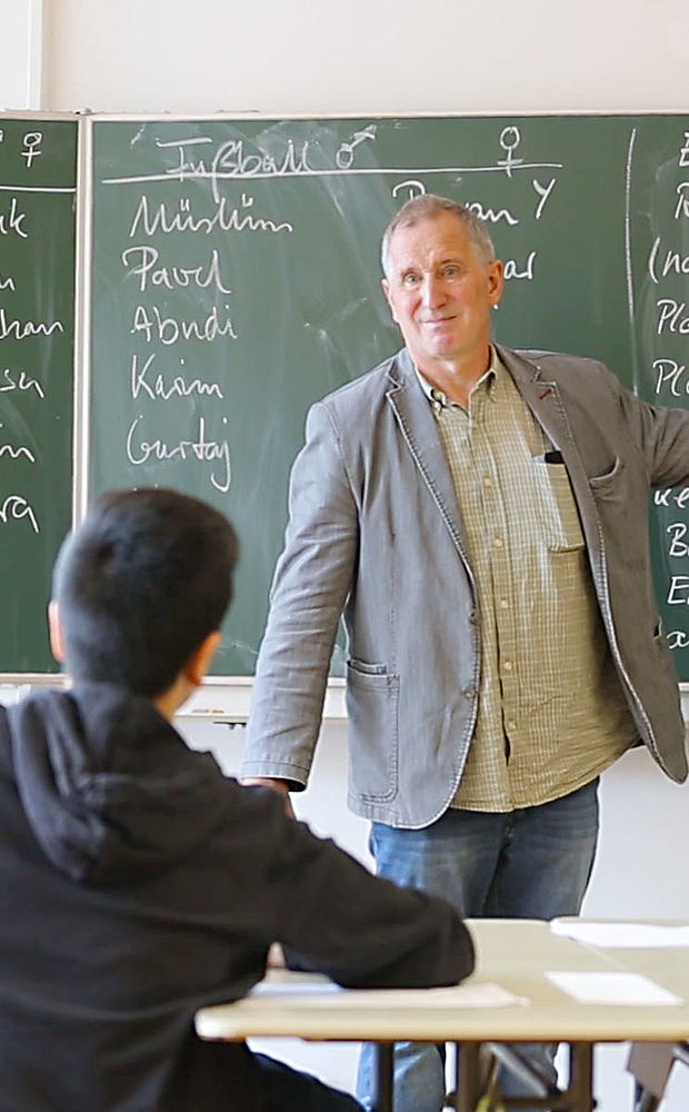 Ein Lehrer zeigt vor Schülern auf die Tafel