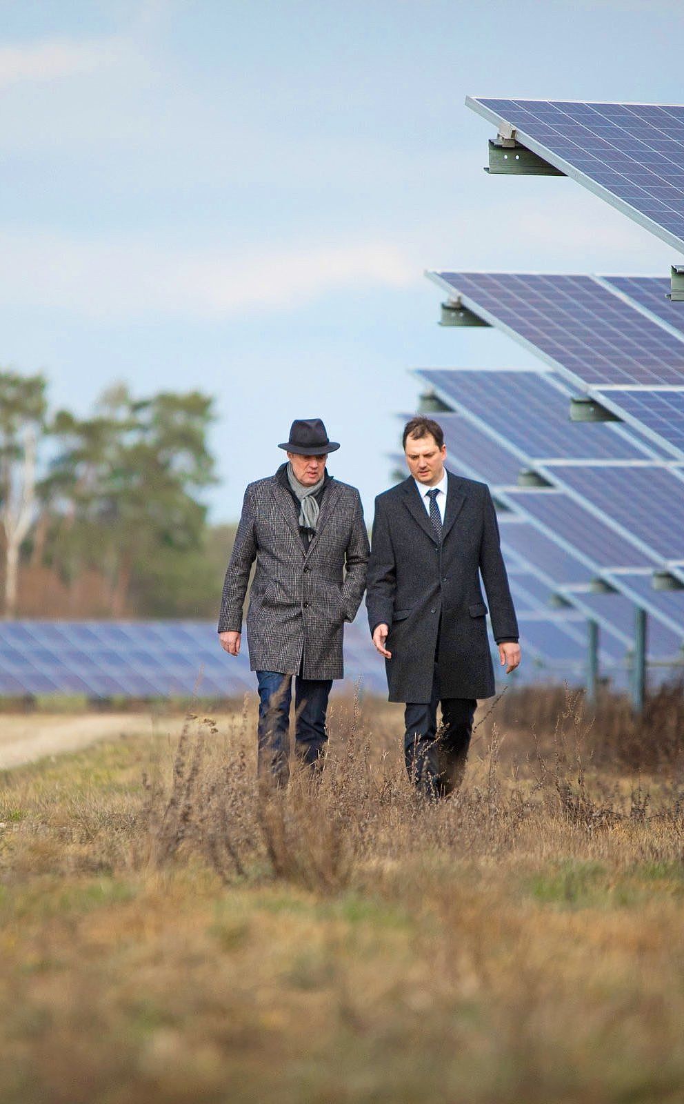 2 Menschen gehen durch einen Solarpark 