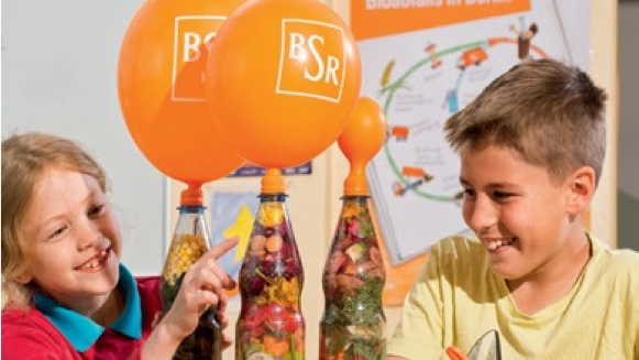 Lachende Kinder mit orangenen BSR Luftballon 
